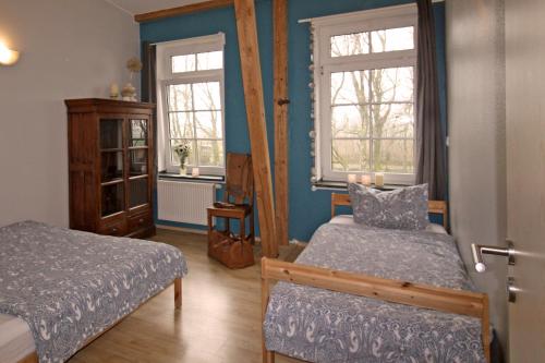 1 dormitorio con 2 camas y 2 ventanas en Ferienwohnungen Poppelvitz, en Altefähr