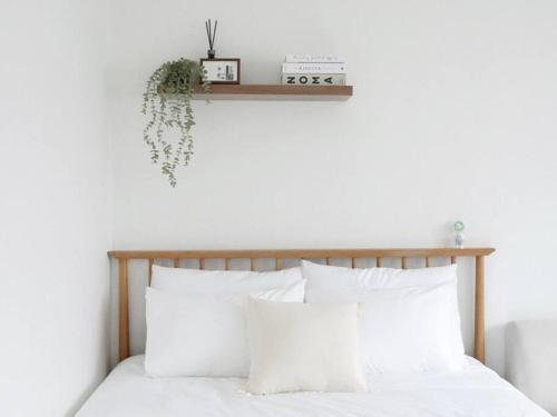 een slaapkamer met een bed met witte kussens en een plank bij KINTEX Daewha Stay Kintex 5min Baek Hospital 1min Daewha Station 5min 킨텍스 대화스테이 in Goyang