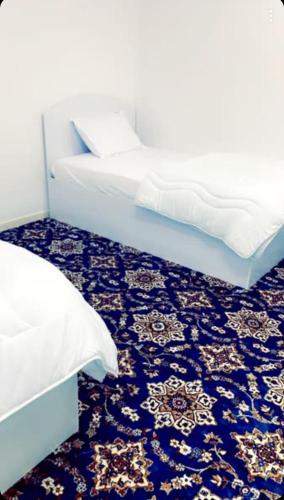 una camera con due letti e un tappeto blu di Madinah Daylight Residences a Medina