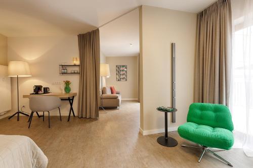 a hotel room with a green chair and a desk at Zur Stadt Mainz - by homekeepers in Würzburg