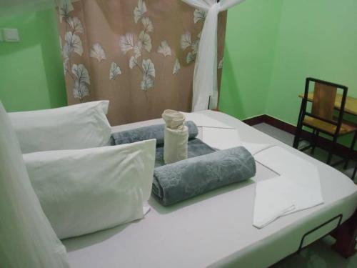 Una cama blanca con almohadas y una botella. en Eyasi Safari Motel, en Mangola