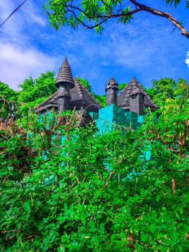 a blue building with turrets in the trees at Châteaux Yolande in Mahajanga