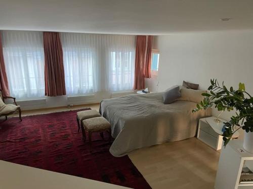 1 dormitorio con 1 cama, 1 silla y ventanas en Atemberaubende Triplexwohnung in der Altstadt Zug en Zug