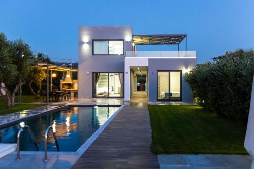 Casa moderna con piscina por la noche en Vilana Exclusive Villas, en Skouloúfia