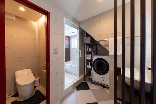 a small bathroom with a toilet and a washing machine at Furano Trailer Village Den in Furano