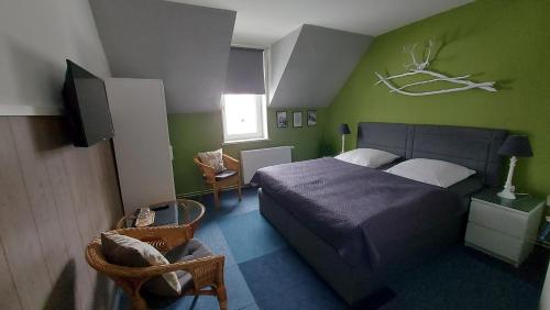 a bedroom with a bed and a green wall at Pension Holl und Boll Am Hexenstieg. in Clausthal-Zellerfeld