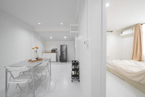 a white room with a bed and a table and chairs at Cozy home near city and air port in Chiang Mai