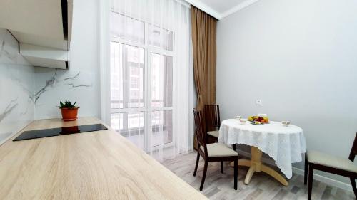 ein Esszimmer mit einem Tisch und einem großen Fenster in der Unterkunft Luxembourg in Taldykolʼ