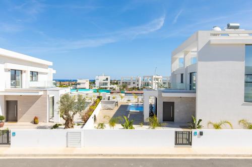 a view of a white house with the ocean in the background at Nelia Panorama Villa in Protaras
