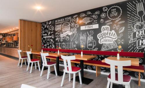 a restaurant with tables and chairs and a chalkboard wall at Hotel Lindenhof in Bielefeld