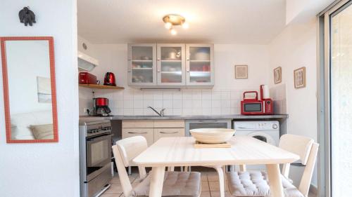 une cuisine avec une table, des chaises et un comptoir dans l'établissement Eleuthera- 171- Appart lumineux 4 pers, au Cap d'Agde