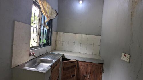una pequeña cocina con fregadero y ventana en Tripple H rent House, en Kilindoni