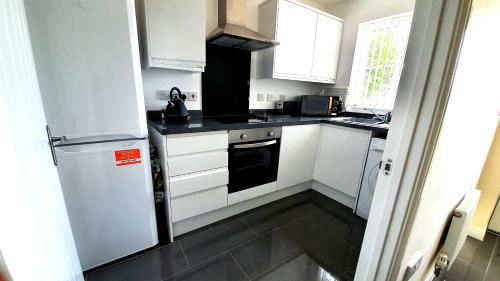 a small kitchen with white cabinets and a refrigerator at Hatley Residencies in Dudley