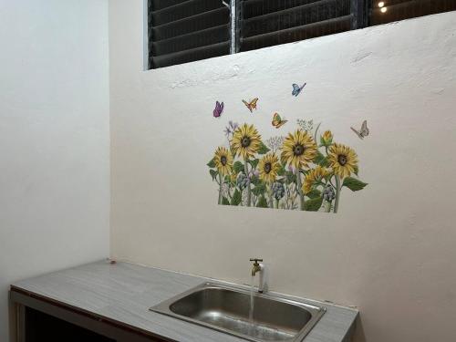 a kitchen sink with a picture of flowers and butterflies at Caishen Modern Affordable Apartelle 202 in Silang