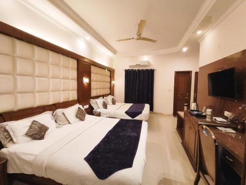a hotel room with two beds and a television at Hotel CJ International in Amritsar