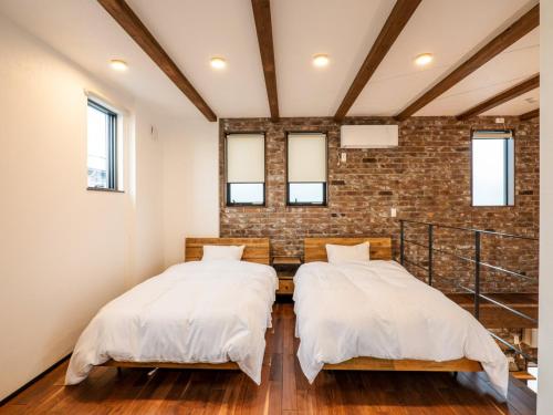 two beds in a room with a brick wall at AMAZING LIFESTYLE GLAMPING HOTEL - Vacation STAY 48572v in Nagahama
