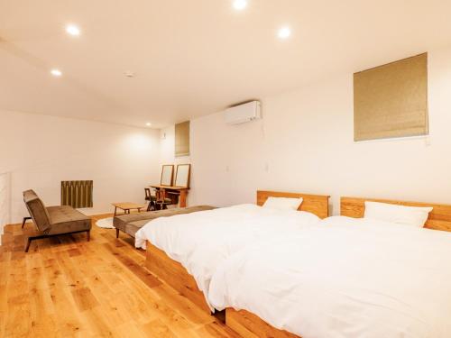 a bedroom with two beds and a chair at AMAZING LIFESTYLE GLAMPING HOTEL - Vacation STAY 44030v in Nagahama
