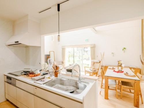 eine weiße Küche mit einem Waschbecken und einem Tisch in der Unterkunft AMAZING LIFESTYLE GLAMPING HOTEL - Vacation STAY 43987v in Nagahama
