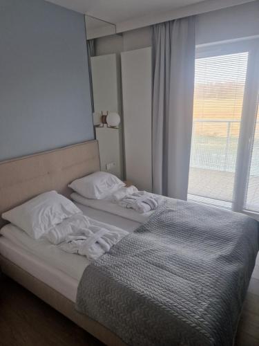 um quarto com uma cama com lençóis brancos e uma janela em Apartament Kołobrzeg Aqua Polanki em Kolobrzeg