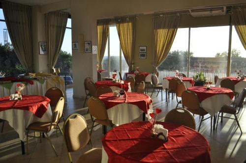 un restaurante con mesas y sillas rojas y blancas en Hotel Golf Internacional en Santa Teresita