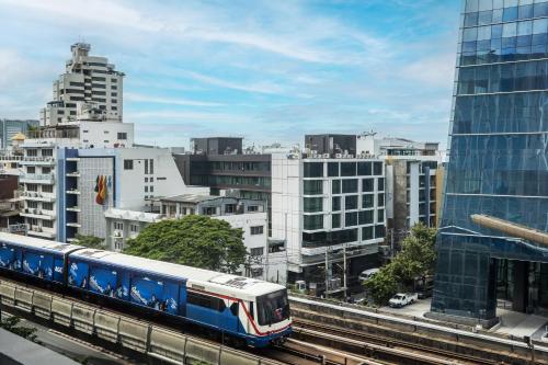 a blue and white train on a track in a city at VIC 3 Bangkok Hotel in Bangkok