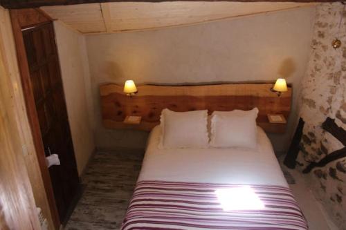 a bed in a room with two lamps on the wall at La casita de Alameda in Alameda del Valle
