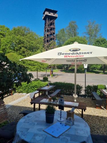 a picnic table with an umbrella in a park at Waldhotel am Turm in Burgholz