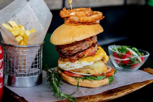 a large hamburger with fried onion rings and french fries at Protea Hotel by Marriott Gaborone Masa Square in Gaborone
