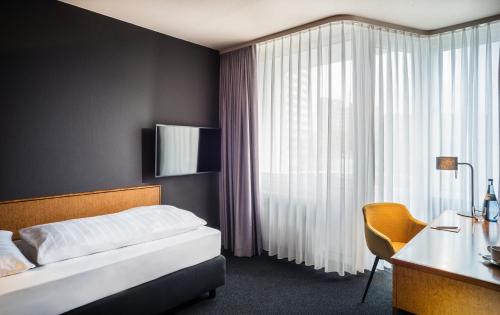 um quarto com uma cama, uma secretária e uma janela em Best Western Hotel Kaiserslautern em Kaiserslautern