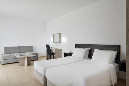 a hotel room with two beds and a desk at Atlantica Callisto in Ayia Napa