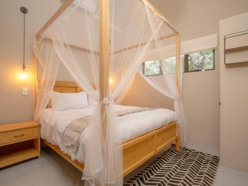 Schlafzimmer mit einem Himmelbett und Moskitonetzen in der Unterkunft Monkeys Tail in Marloth Park