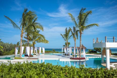 a resort swimming pool with palm trees and a beach at Ycona Eco-Luxury Resort, Zanzibar in Dikoni