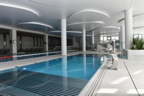 a large swimming pool with blue water in a building at Apartament D013 Polanki Aqua in Kołobrzeg