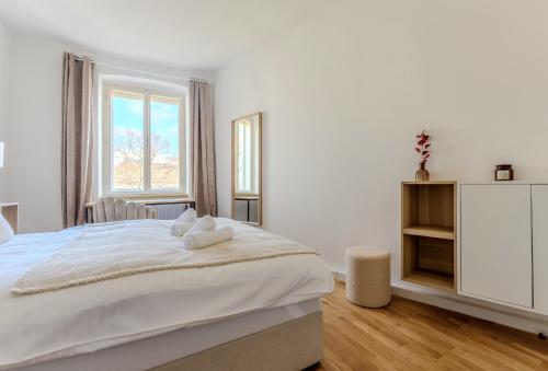 a white bedroom with a large bed and a window at UrbanSuite in der Innenstadt in Krems an der Donau