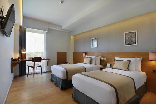 a hotel room with two beds and a desk at Azana Boutique Hotel Denpasar in Denpasar