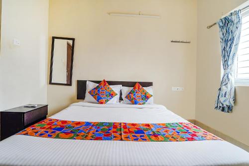 sypialnia z dużym łóżkiem i kolorowym kocem w obiekcie FabExpress Vangal Nest w mieście Pīlamedu