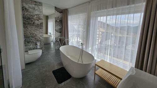 a bathroom with two tubs and a large window at Bormio - Czarna Góra Resort by Sun & Snow z nielimitowanym basenem in Sienna
