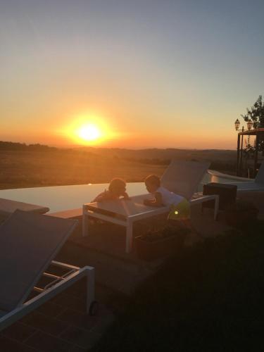 two people sitting on a bed with the sunset in the background at Agriturismo Il Macchione in Pienza