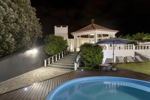 a swimming pool in front of a house at night at Quinta das Rosas Villas in Ribeira Grande