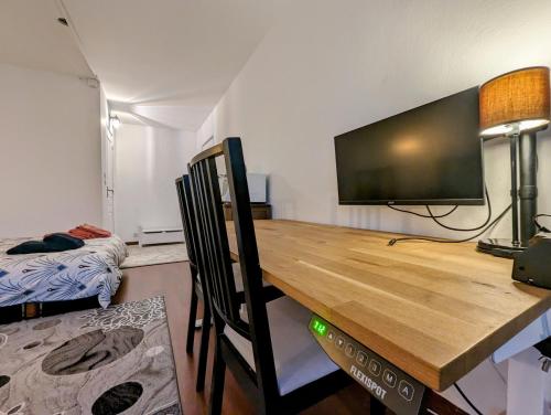a room with a wooden desk with a television on the wall at Chez les P'tits loups in Strasbourg