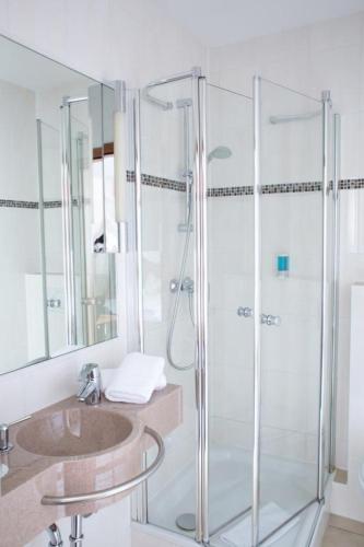 a bathroom with a glass shower and a sink at Hotel Panorama in Heidelberg