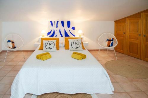 a bedroom with a white bed with yellow pillows at Le Charme de l'Orée des Lices in Carcassonne