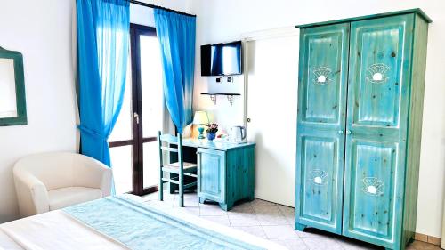 a bedroom with a blue cabinet and a desk at La Perla Hotel in SantʼAnna Arresi