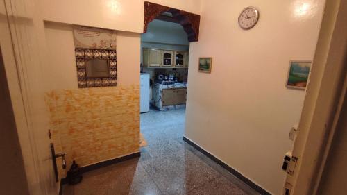 um corredor que leva a uma cozinha com um relógio na parede em Residence Gharnata app 11 imm I em Marrakech