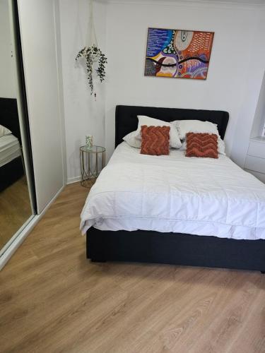 een slaapkamer met een bed met witte lakens en bruine kussens bij 1 bedroom, self contained apartment in resort complex in Caloundra