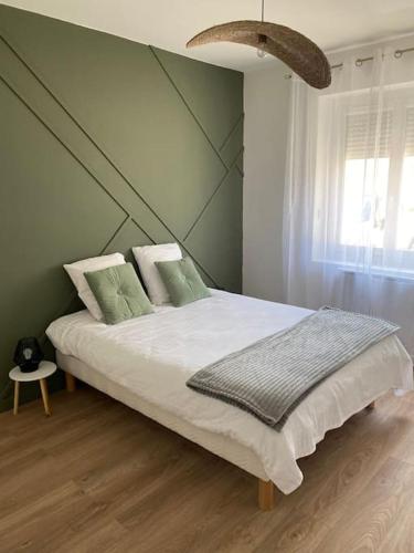 - une chambre avec un grand lit blanc et des oreillers verts dans l'établissement Saint-Laurent-20 min Lyon-proche Aéroport-Eurexpo, à Saint-Laurent-de-Mure