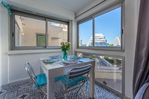 une pièce avec une table, des chaises et des fenêtres dans l'établissement La Petite Vague - Appt à moins d'un km de la plage, à La Grande Motte