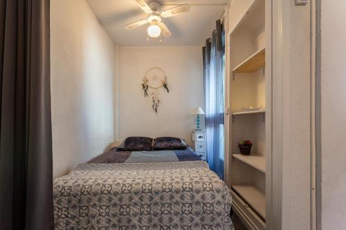 - une petite chambre avec un lit et un ventilateur de plafond dans l'établissement La Petite Vague - Appt à moins d'un km de la plage, à La Grande Motte