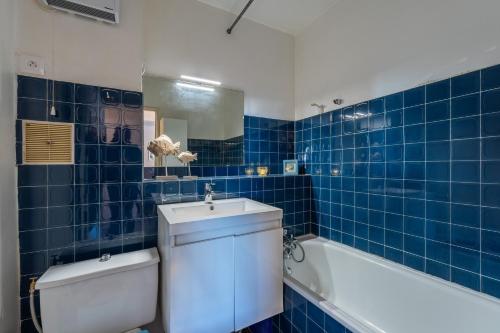 La salle de bains est pourvue de carrelage bleu, de toilettes et d'un lavabo. dans l'établissement La Petite Vague - Appt à moins d'un km de la plage, à La Grande Motte