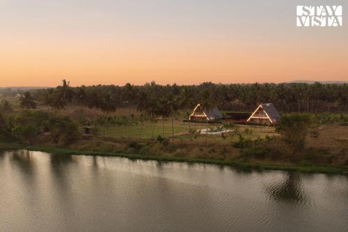a group of tents next to a river at sunset at Golden Apex by VEO - Part of StayVista in Hampāpura